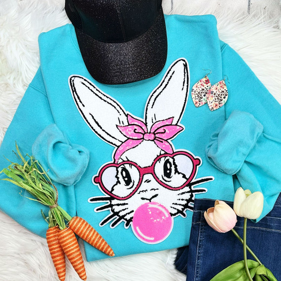 Bunny with Glasses Chenille Patch, a colorful embroidered patch of a cute bunny wearing pink glasses and a pink bow, on a blue sweatshirt.