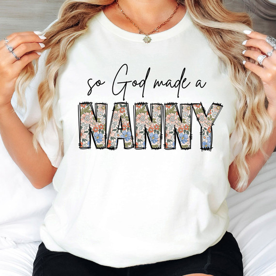 So God Made A Nanny DTF Heat Transfer, floral patterned text on a white T-shirt with the phrase 'so God made a NANNY' in stylish black script and bold multicolored floral letters.