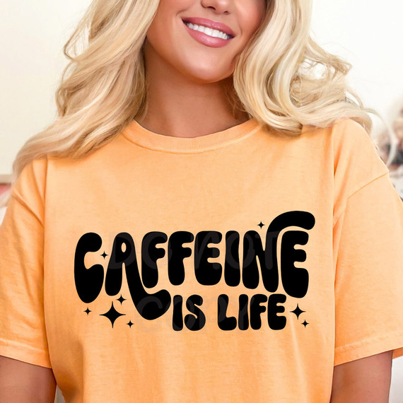 Caffeine Is Life DTF Heat Transfer, woman wearing orange t-shirt with black caffeine is life slogan and decorative stars.