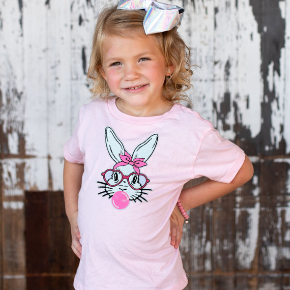 YOUTH Bunny with Glasses Chenille Patch, Young girl wearing pink t-shirt with bunny graphic and chenille patch, outdoor background.