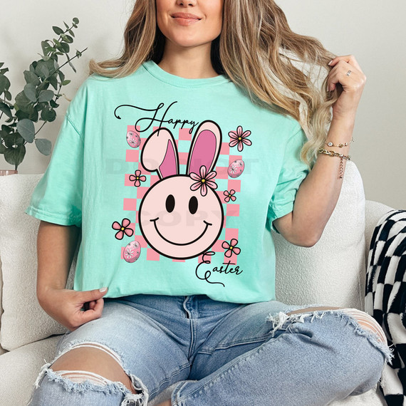 Happy Easter Bunny Happy Face DTF Heat Transfer, colorful design featuring a smiling bunny face with pink ears, surrounded by flowers and Easter eggs on a light teal t-shirt.