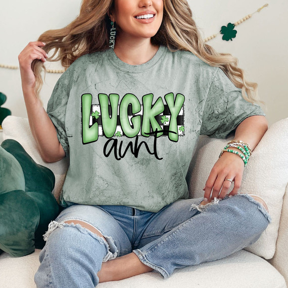 Lucky Aunt Retro DTF Heat Transfer, woman wearing a grey t-shirt with green and black lettering, celebrating St. Patrick's Day with shamrock decorations.
