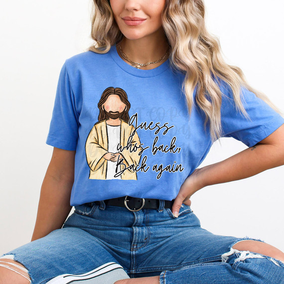 Guess Who's Back Back Again DTF Heat Transfer, a woman wearing a blue T-shirt with a cartoon Jesus illustration and the text 'Guess who's back, Back again'.