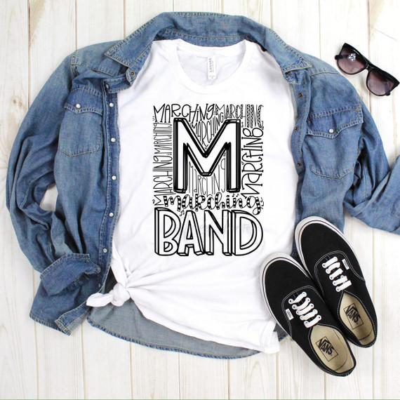 Marching Band typography Sublimation Transfer, displayed on a white t-shirt with a large stylized 'M' and 'B' surrounded by the words 'Marching' and 'Band' in different fonts and sizes.