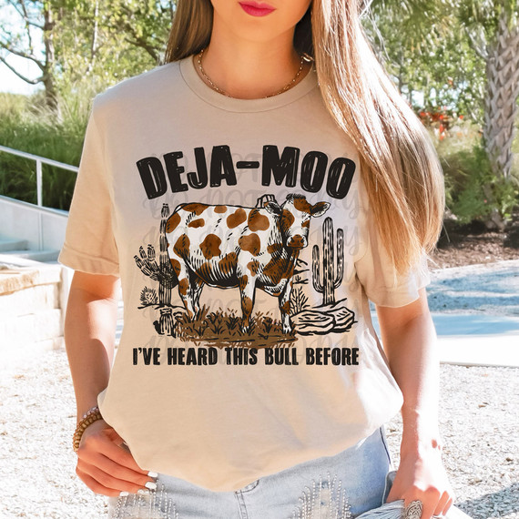 Deja-Moo DTF Heat Transfer, a humorous cow design on a beige T-shirt with text and cartoon-style graphic.