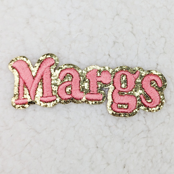 Margs Embroidered Glitter HAT/POCKET Patch, pink embroidered patch with the word 'Margs' outlined in gold glitter.