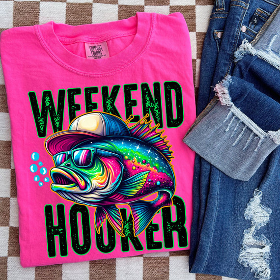 Weekend Hooker DTF Heat Transfer, colorful fish graphic on a pink T-shirt with distressed denim jeans nearby.