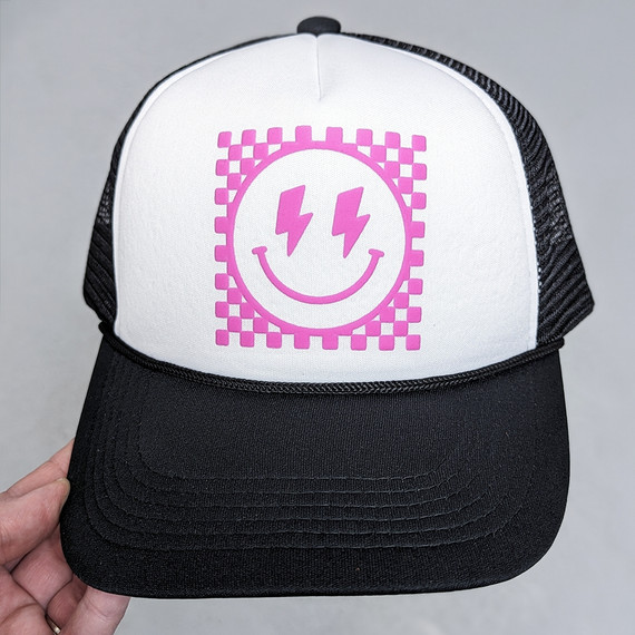 Checkered Happy Face PINK PUFF Hat/Pocket Screen Print Heat Transfer, a trucker-style cap with a pink smiley face featuring lightning bolt eyes on a white front panel with black brim and mesh back.