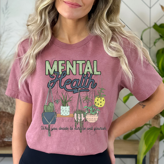 Mental Health What You Decide To Nurture Will Flourish DTF Heat Transfer, a woman wearing a pink T-shirt with a design of hanging potted plants and the motivational quote about nurturing mental health.