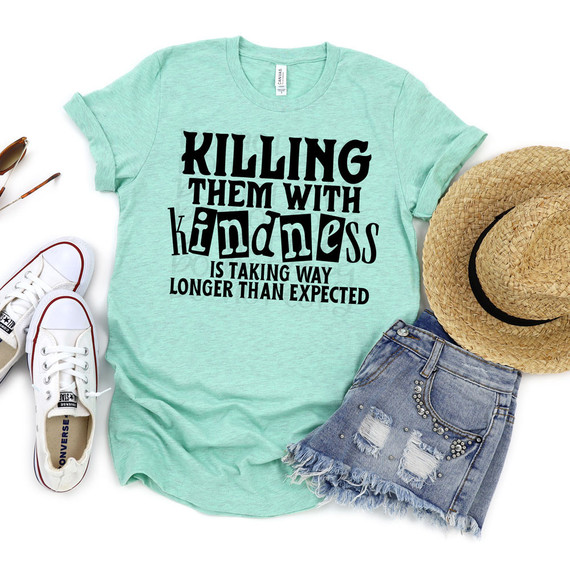 Killing Them With Kindness Is Taking Longer Than Expected DTF Heat Transfer, mint green T-shirt with bold black and blue text for positive message, paired with denim shorts, white sneakers, and a straw hat, ideal for casual summer wear.