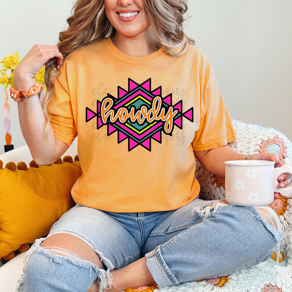 Howdy Aztec DTF Heat Transfer, colorful Native American inspired geometric design with the word 'Howdy' on a yellow t-shirt worn by a smiling woman.