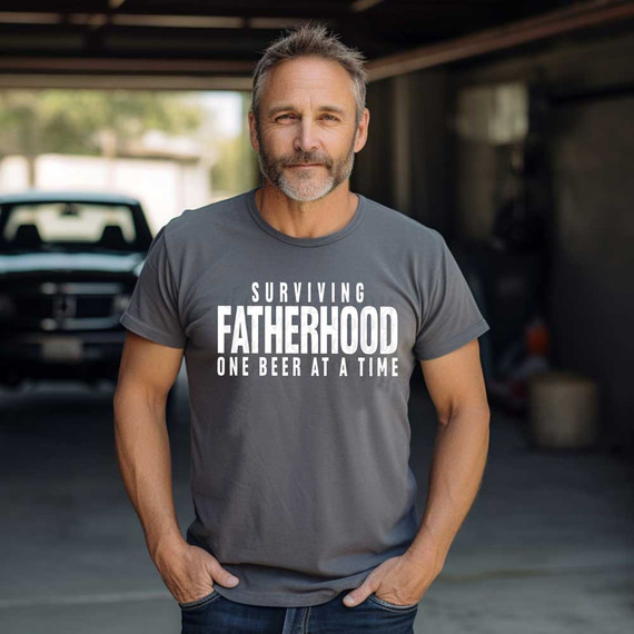 Surviving Fatherhood WHITE DTF Heat Transfer, a man wearing a gray T-shirt with the text 'Surviving Fatherhood One Beer at a Time' printed on it.