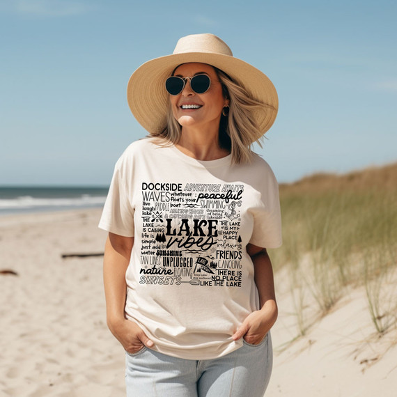 Lake Vibes Text DTF Heat Transfer, a woman on the beach wearing a white t-shirt with lake-themed text and graphics.