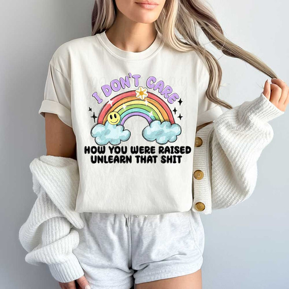 I Don't Care How You Were Raised Unlearn That Shit DTF Heat Transfer, a graphic tee with colorful rainbow, clouds, smiley face, and text design.