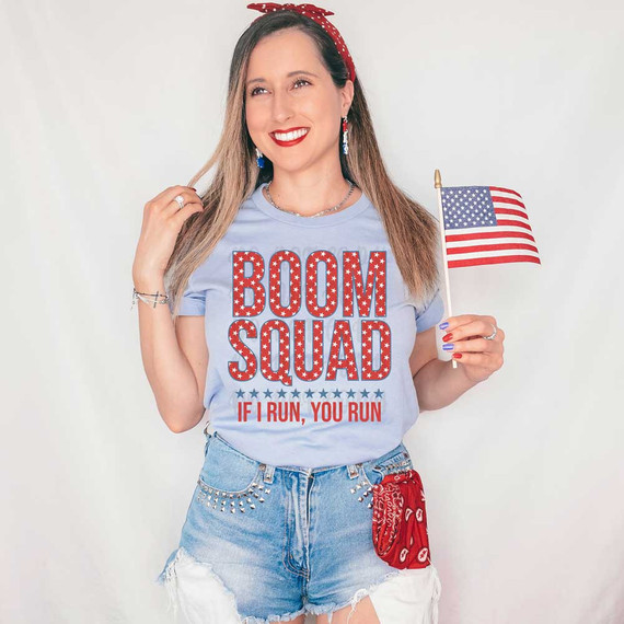 Boom Squad If I Run, You Run DTF Heat Transfer, a woman wearing a patriotic-themed t-shirt with the design, holding an American flag.