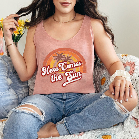 Here Comes The Sun Retro DTF Heat Transfer, a woman wearing a pink tank top showcasing the retro sunset sun and palm trees design with the phrase 'Here Comes The Sun' on it.