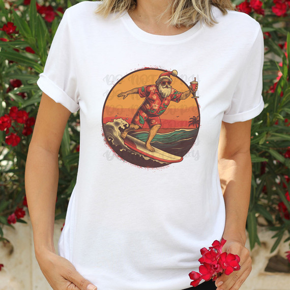 Surfing Santa DTF Heat Transfer on T-shirt, humorous Christmas Santa with beard, sunglasses, tropical shirt, surfing on a wave while holding a drink, sunset background.