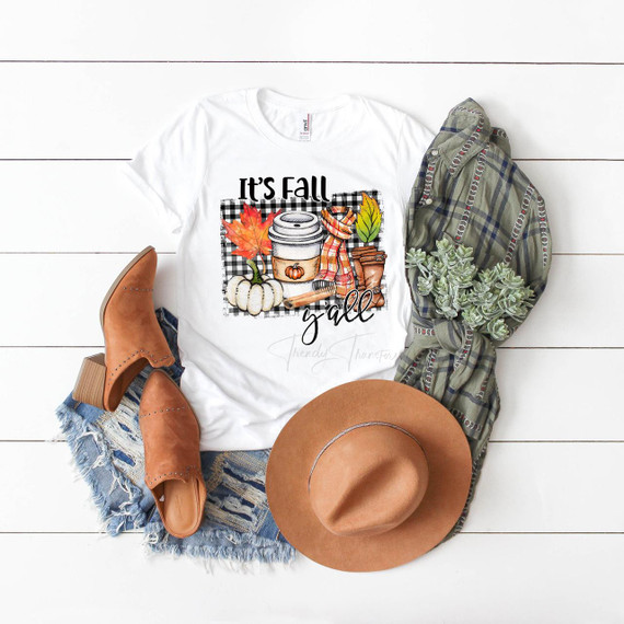 It's Fall Ya'll plaid cinnamon pumpkin spice sublimation transfer T-shirt with autumn-themed design, surrounded by a pair of tan boots, a brown hat, a plaid shirt, and a small succulent plant.