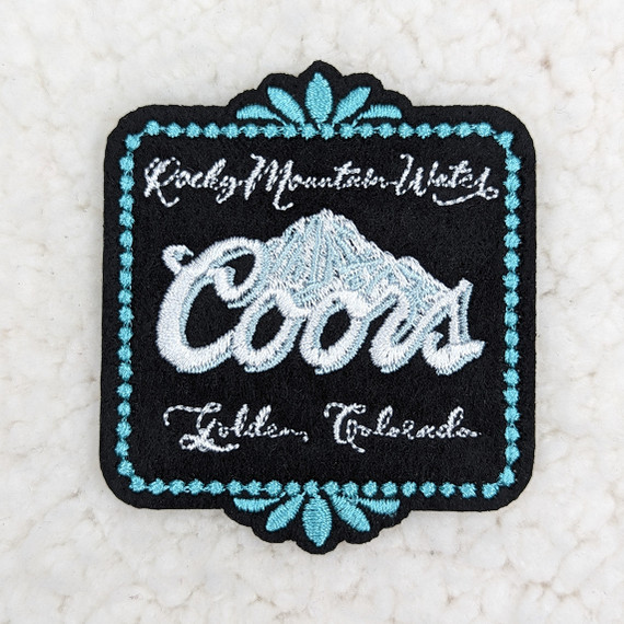 Coors BLACK Embroidered HAT/POCKET Patch, black fabric patch featuring embroidered blue and white design including the Coors logo, mountain graphic, and decorative border.