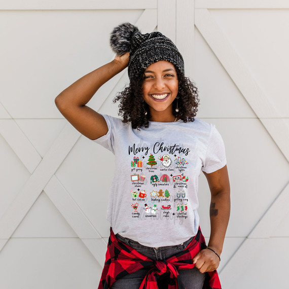 Christmas Favorites DTF Heat Transfer, cheerful woman wearing a holiday-themed T-shirt with Christmas icons and text, smiling and adjusting her festive hat.