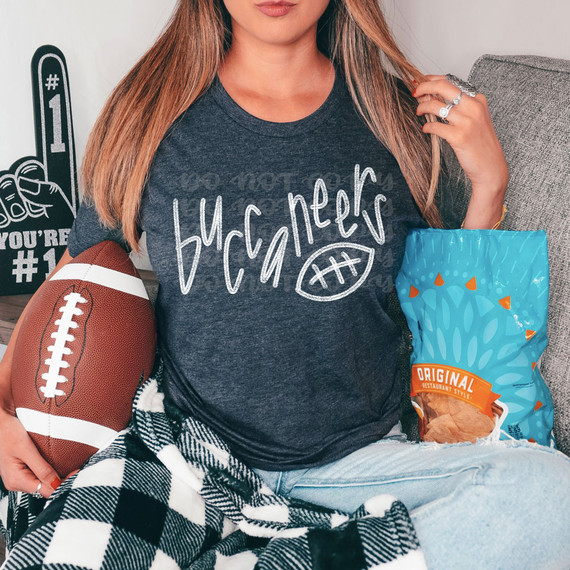 Buccaneers Football WHITE DTF Heat Transfer, white heat transfer decal on a dark gray t-shirt featuring a playful handwritten Buccaneers logo and football icon.