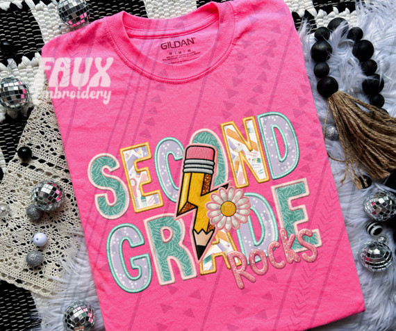 Second Grade Rocks Pink DTF Heat Transfer, colorful educational illustration on pink fabric with graphics of a pencil, daisy flower, and bold letters.