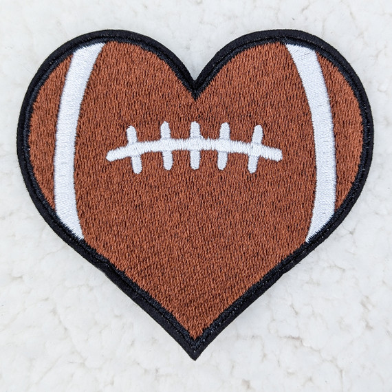 Football Heart Embroidered HAT/POCKET Patch, brown heart-shaped patch featuring a white football seam design with a black border.