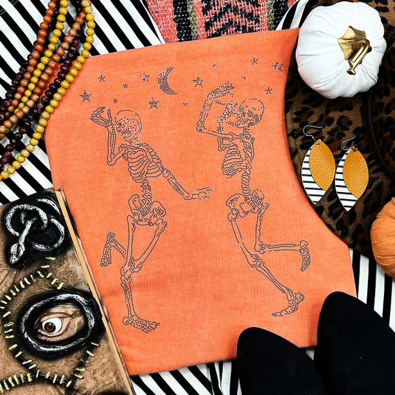 Spangled Dancing Skeletons Heat Transfer, orange fabric with black skeletons dancing under a moon and stars design.