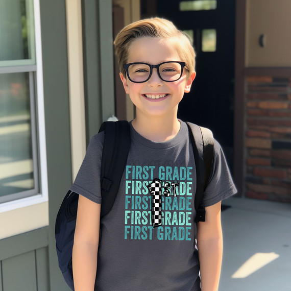 First Grade Checker DTF Heat Transfer, image of a young boy with glasses smiling and wearing a gray t-shirt with the word 'First Grade' repeated and a large number one in checkerboard pattern.
