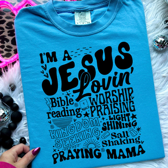 Jesus Lovin' Mama DTF Heat Transfer, Black text and graphics on a blue T-shirt with religious and worship-themed words and illustrations.