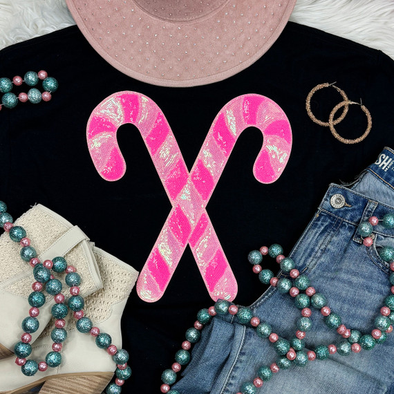 Pink Sequins Candy Canes Patch, shiny pink sequin candy cane shaped patch on black shirt surrounded by blue and pink bead necklaces, denim shorts, pink hat, and earrings.