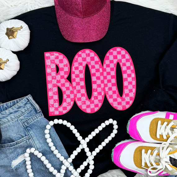 Checkered Pink BOO Sequin Patch, close-up of a pink checkered sequin patch spelling 'BOO' on a black t-shirt, with sneakers, denim shorts, white beads, and white pumpkins in the background.