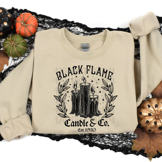Black Flame Candle & Co BLACK DTF Heat Transfer, a printed design of black candles with melting wax, flames, and decorative leaves on a beige sweatshirt.