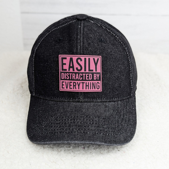 Easily Distracted By Everything FAUX Leather Patch, black baseball cap with pink and black embroidered patch displaying the text 'Easily Distracted By Everything'.