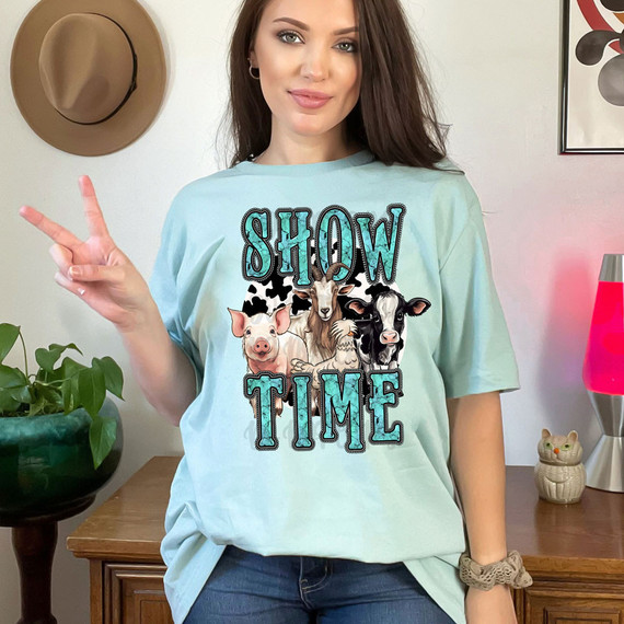Show Time Farm Animals DTF Heat Transfer, image of a woman wearing a light blue t-shirt with farm animal illustrations and the text 'SHOW TIME'.