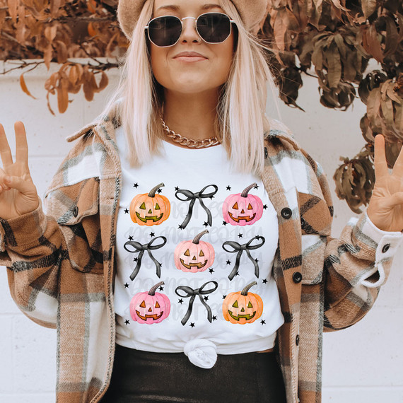Pumpkin Coquette DTF Heat Transfer, a design featuring colorful carved pumpkins with bows and stars on a woman's white t-shirt.