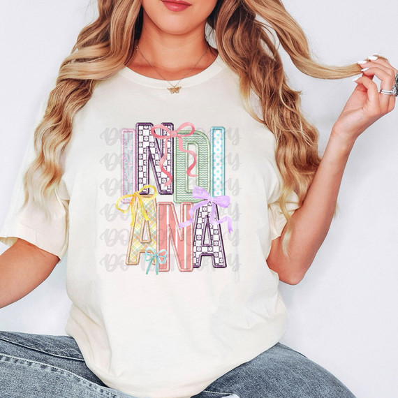 Indiana Coquette Faux Embroidery DTF Heat Transfer, colorful embroidered letters spelling 'MAY BE' on a white t-shirt, with pastel ribbons and decorative patterns.