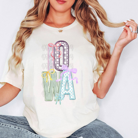 Iowa Coquette Faux Embroidery DTF Heat Transfer, colorful embroidered design of the number 0 and the letters W and A with bows, on a white t-shirt worn by a woman with blonde hair.