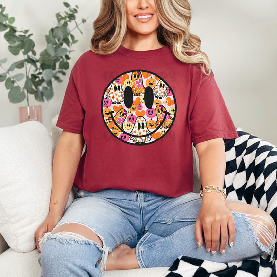 Ghost Happy Face DTF Heat Transfer, a colorful halloween-themed smiling face made of pumpkins, ghosts, and other spooky elements on a dark background.