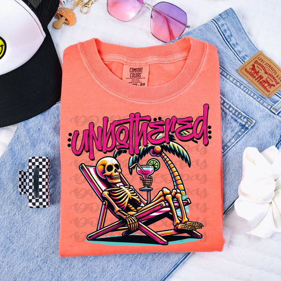 Unbothered Skeleton DTF Heat Transfer, colorful skeleton sitting on a lounge chair with a tropical drink, on a coral pink T-shirt.