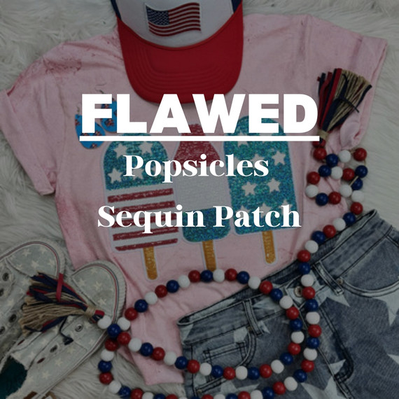 FLAWED Popsicles Sequin Patch, colorful sequin ice cream popsicle design on a pink t-shirt with patriotic accessories around, including a red, white, and blue beaded necklace, a cap with an American flag, and sneakers.
