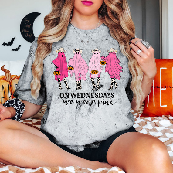 On Wednesday We Wear Pink Ghosts DTF Heat Transfer T-shirt, graphic tee featuring cute pink ghost characters dressed as cows with pumpkin baskets, celebrating Halloween and the phrase 'On Wednesdays we wear pink'.