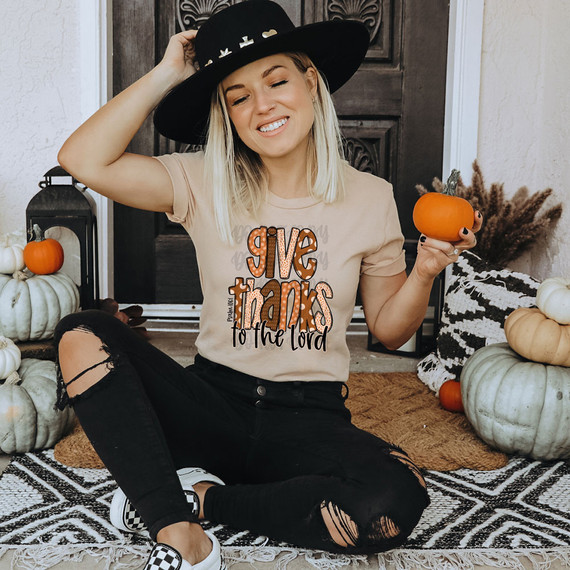 Give Thanks To The Lord Polka Dots DTF Heat Transfer, a woman holding pumpkins and wearing a T-shirt with thankfulness message, surrounded by fall decorations.