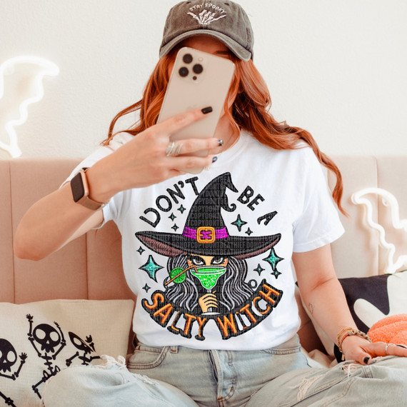 Don't Be A Salty Witch Faux Embroidery DTF Heat Transfer, colorful embroidered witch design with text on a white T-shirt worn by a woman taking a selfie.
