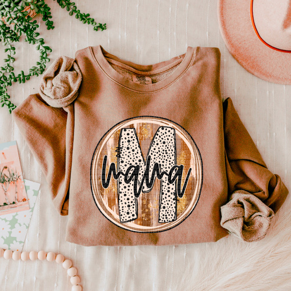 Mama Fall Brushstrokes DTF Heat Transfer, embroidered design on a peach-colored sweatshirt with the letter M and the name 'Mama' in black cursive font.