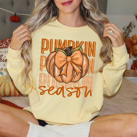 Pumpkin Season Stacked DTF Heat Transfer, image of a woman showcasing a tan pumpkin applique with a bow on her yellow sweatshirt, seasonal fall design art for pumpkin season.