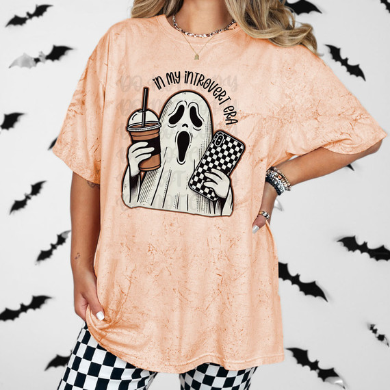 In My Introvert Era Halloween DTF Heat Transfer, Halloween-themed ghost design on a peach-colored shirt with a ghost holding a coffee drink and a phone, perfect for introverts and Halloween celebrations.