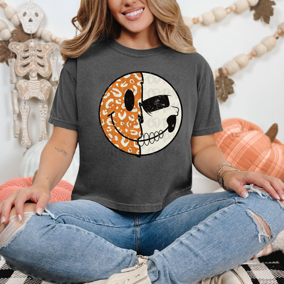 Halloween Face DTF Heat Transfer, a woman wearing a dark gray T-shirt with a skull graphic divided into a leopard print and a plain design, in a festive Halloween decorated room.