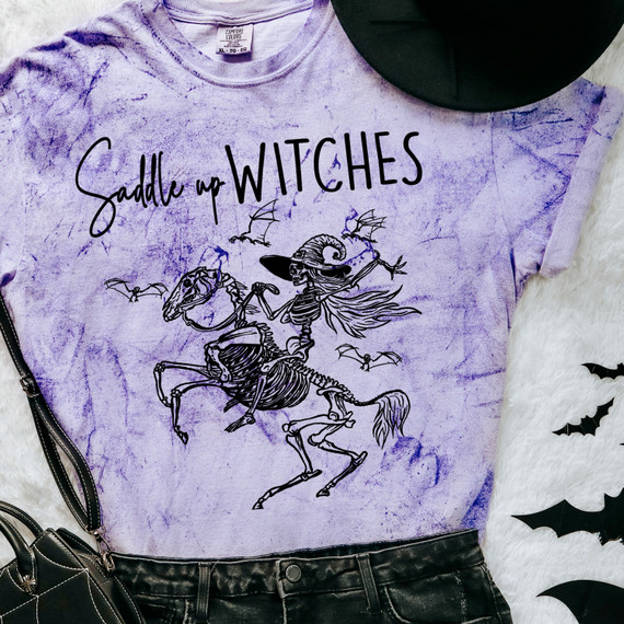 Saddle Up Witches DTF Heat Transfer, Halloween themed purple tie-dye T-shirt with a skeleton witch riding a horse and flying bats.