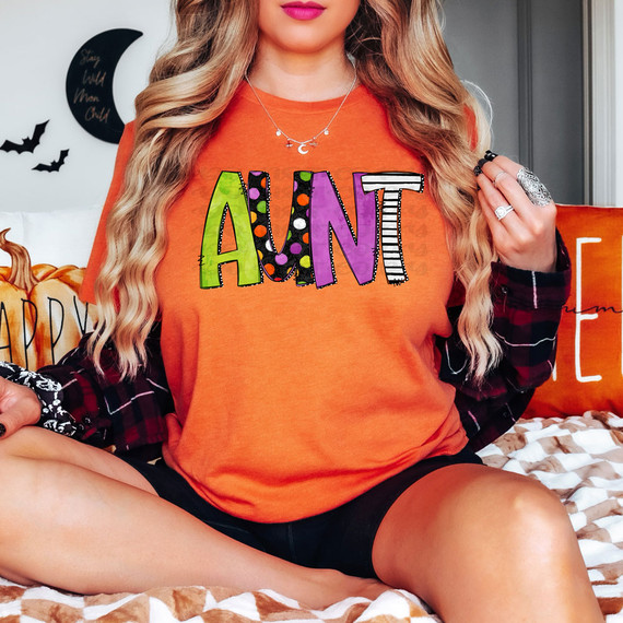 Aunt Halloween Letters DTF Heat Transfer, colorful and spooky Halloween-themed rainbow letters on a woman's orange T-shirt.
